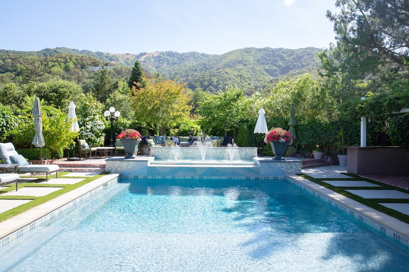 The finished pool with fountain wall, planting, and hillside views