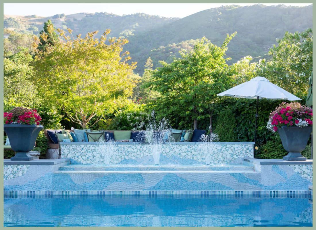 Pool terrace framed by layered planting with hillside views beyond